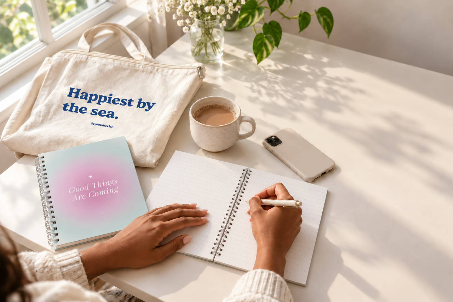 Writing in the Good Things Are Coming notebook next to the Happiest by the Sea tote